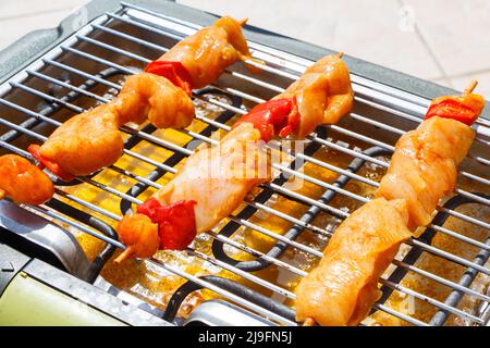 Brochette de poulet mariné sur la grille d'un barbecue électrique en été Banque D'Images