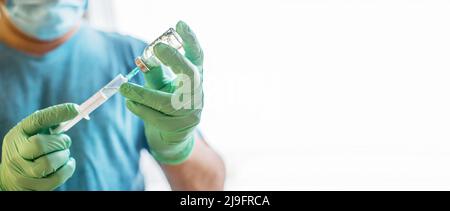 Mains du médecin remplissant une seringue. Homme mains dans des gants bleus tenant le vaccin. Médecine, vaccination et concept de drogue. Médicament flacon dose injection. Banque D'Images