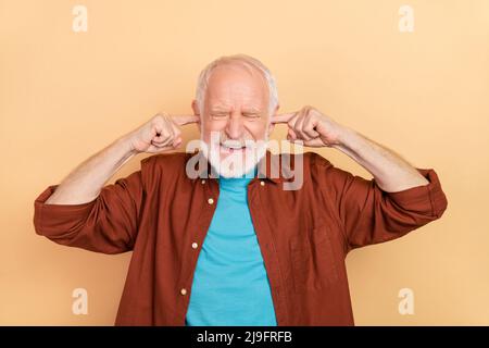 Photo de l'aîné stressé blanc coiffure homme proche oreilles porter une tenue marron isolé sur fond beige couleur Banque D'Images