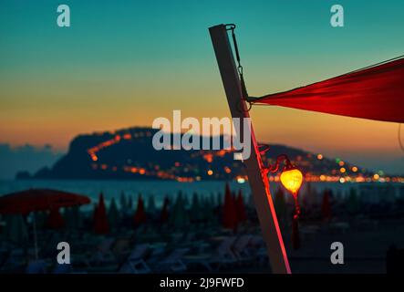 Lanterne sur la plage au coucher du soleil avec péninsule d'Alanya sur le fond Banque D'Images