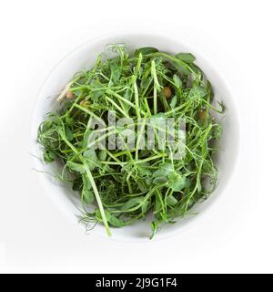 Microverts frais de pois dans un bol blanc isolé sur fond blanc Banque D'Images