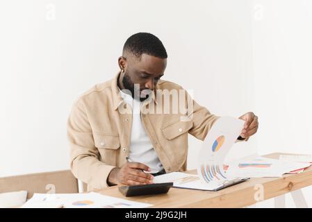 Un jeune Afro-américain lit une lettre d'une banque au sujet de problèmes financiers liés à la dette de crédit. Black man découvre les problèmes budgétaires, se sent frustré Banque D'Images