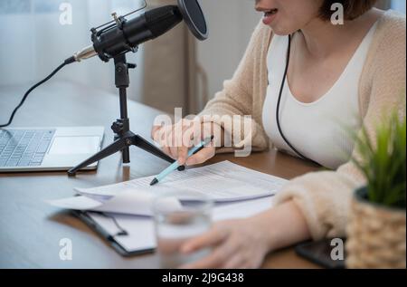 Femme parlant de façon expressive avec des gestes de la main dans un microphone au bureau. Banque D'Images