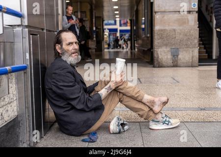 Un homme sans domicile avec le pied infecté s'assit supplier de l'argent à l'extérieur de Victoria Station, Londres, Royaume-Uni Banque D'Images