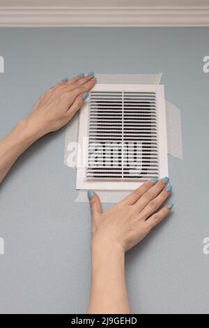 fixe à la main une grille de ventilation collée au mur. Photo de haute qualité Banque D'Images