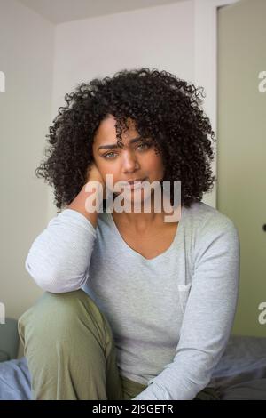 Smiling woman sitting on bed Banque D'Images