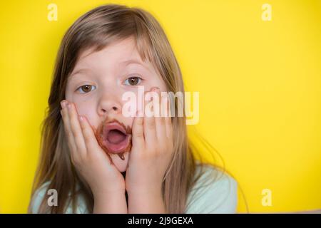 Petite fille effrayée mangeant chocolat sale visage Banque D'Images