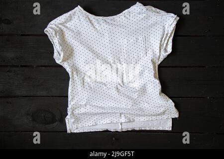 t-shirt blanc avec pois noirs sur une table en bois noir, t-shirt blanc Banque D'Images