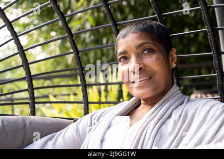 Femme mûre souriante assise sur un fauteuil pivotant Banque D'Images