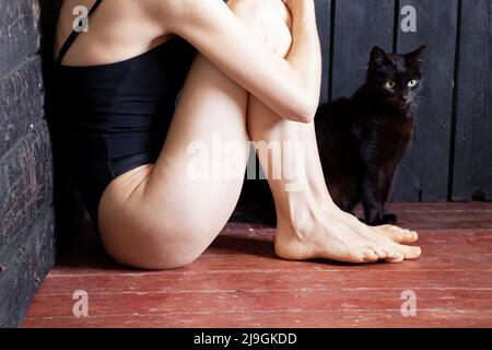 une fille est assise dans le coin de la pièce, effrayée par la dépression et un chat est debout à côté d'elle, une mauvaise humeur et la solitude Banque D'Images