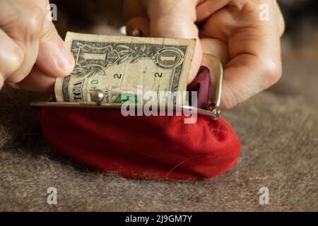 les mains de la vieille femme prennent une facture de dollar d'un portefeuille rouge doux, l'argent dans un portefeuille, la finance Banque D'Images