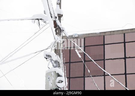 Fils électriques dans la neige avec de la glace sur un poteau dans un quartier résidentiel de la ville, les fils de la gravité de la neige dans la ville de Dnipro à Ukra Banque D'Images