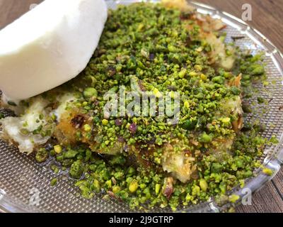 Dessert, Kunefe qui est un dessert turc traditionnel cuit avec du fromage à l'intérieur servi avec de la pistache et de la glace en Turquie. Mets turcs sucrés Banque D'Images