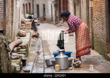 Katmandou, Népal- 20 avril, 2022 : les femmes lavent les vêtements et les plats dans les rues de la place Patan Durbar. Banque D'Images