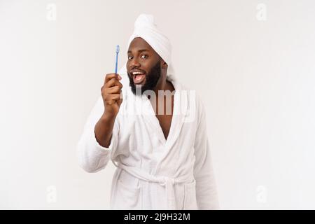 portrait d'un heureux jeune anm foncé se brossant les dents avec du dentifrice noir sur fond blanc. Banque D'Images