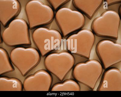 Motif de confiseries romantiques au chocolat en forme de coeur sur fond jaune pastel. Motif coeur lait chocolat pralines sucreries sur fond de champagne beige. Vue de dessus ou plan de travail Banque D'Images