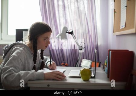 L'adolescent étudie à distance via Internet à l'aide d'un ordinateur portable. Banque D'Images