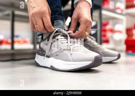 une fille essaie de nouvelles baskets dans un magasin de vêtements de sport Banque D'Images