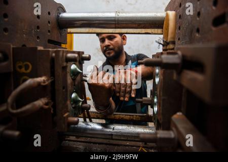 New Delhi, Inde. 23rd mai 2022. Un travailleur répare une machine de moulage automatique dans une usine de fabrication de produits en plastique à New Delhi. Crédit : SOPA Images Limited/Alamy Live News Banque D'Images