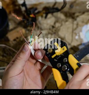 Utilisation de l'outil pour la dépose de l'isolation pour la dépose de l'extrémité d'un fil électrique lors de la réparation et de la mise à jour du câblage électrique d'une maison électrique Banque D'Images