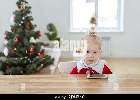 Enfant sourd fille avec implant cochléaire dans la salle de séjour avec espace de copie d'arbre de noël et endroit pour la publicité - diversité de surdité et innovation Banque D'Images