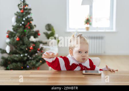 Enfant fille vêtue d'une robe de noël avec implants cochléaires s'amusant à la maison - diversité et aide auditive et technologies innovantes pour le traitement Banque D'Images