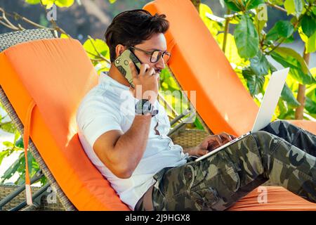 homme parlant au téléphone inde vacances d'été.élégant jeune indien indépendant travaillant avec ordinateur portable freelance surf en ligne.homme d'affaires à distance Banque D'Images