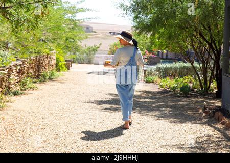 Femme portant une combinaison marchant dans le jardin le jour ensoleillé Banque D'Images