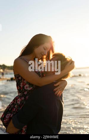 Un jeune couple s'embrassant à la plage par beau temps Banque D'Images
