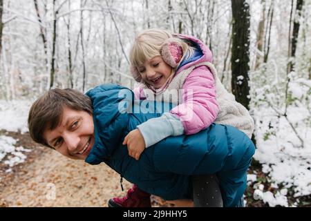 Père fille porcgysoutenant dans la forêt d'hiver Banque D'Images