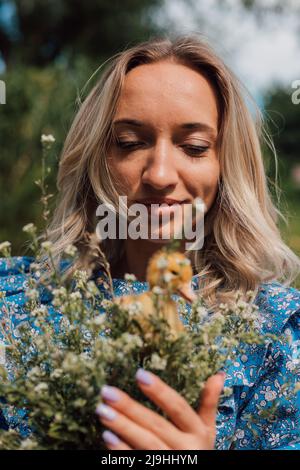 Belle fille tenant des fleurs sauvages et des canetons dans ses mains Banque D'Images