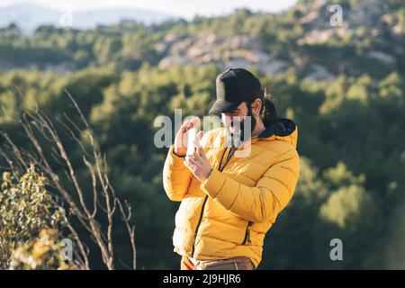 Un homme heureux portant une casquette qui photographie par smartphone par beau temps Banque D'Images