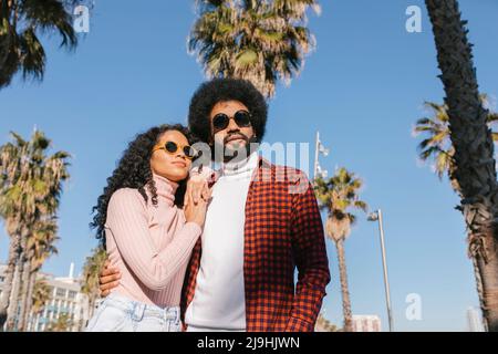 Couple souriant portant des lunettes de soleil par temps ensoleillé Banque D'Images