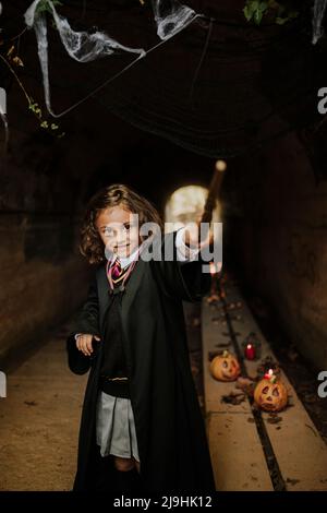 Fille souriante portant un costume de sorcière s'amusant dans le tunnel à Halloween Banque D'Images