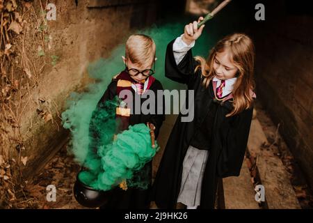 Fille avec frère tenant le chou-fleur et baguette magique debout au milieu de la fumée verte dans le tunnel Banque D'Images