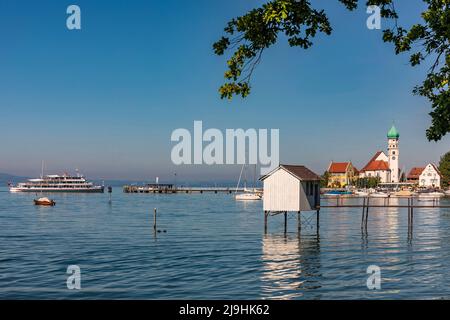 Allemagne, Bavière, Wasserburg am Bodensee, rive du lac de Constance avec maison à pilotis en premier plan et église de Saint George en arrière-plan Banque D'Images