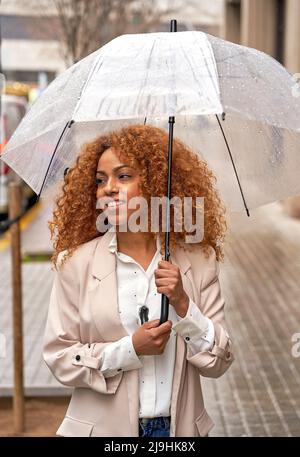 Jeune femme d'affaires marchant dans la rue tenant un parapluie Banque D'Images