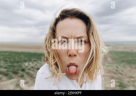 Une femme espiègle qui colle à la langue sur le terrain agricole Banque D'Images