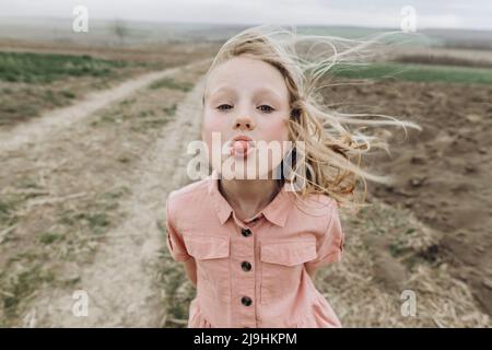 Fille qui colle la langue sur le terrain agricole Banque D'Images
