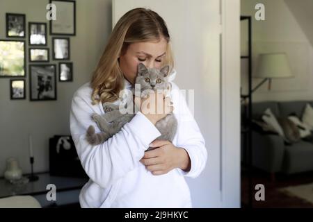 Jeune femme embrassant chat gris à la maison Banque D'Images