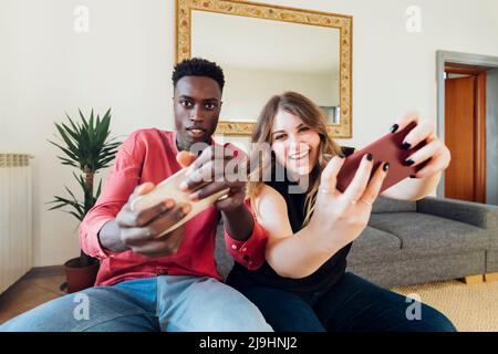 Couple heureux jouant à des jeux vidéo sur smartphone à la maison Banque D'Images