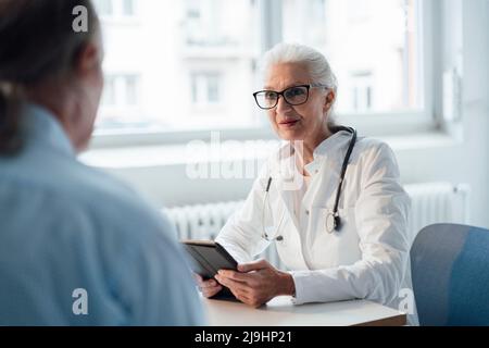 Médecin discutant avec le patient assis à son bureau Banque D'Images