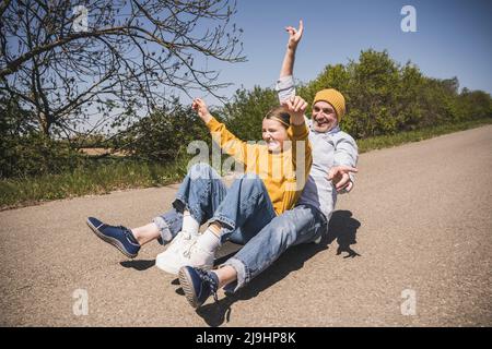 Joyeux homme senior qui fait du skateboard avec sa petite-fille par beau temps Banque D'Images