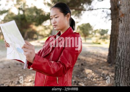 Jeune femme lisant une carte en forêt Banque D'Images