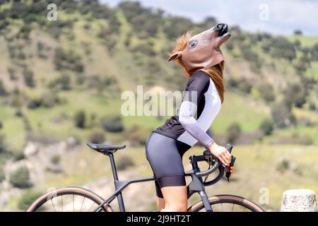 Cycliste avec vélo portant un masque de cheval le jour ensoleillé Banque D'Images