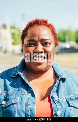 Souriant avec des cheveux rouges teints par temps ensoleillé Banque D'Images