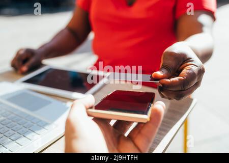 Client effectuant un paiement sans contact par carte de crédit au café Sidewalk Banque D'Images