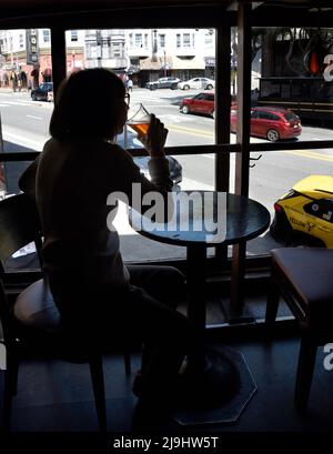 Une femme apprécie une bière au Vesuvio Cafe, un bar américain de renom dans la partie de North Beach de San Francisco, en Californie. Banque D'Images