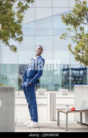 Homme d'affaires avec les mains dans les poches penchées vers l'arrière sur la marche Banque D'Images