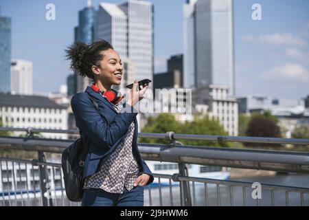 Jeune femme d'affaires envoyant la messagerie vocale par téléphone mobile Banque D'Images